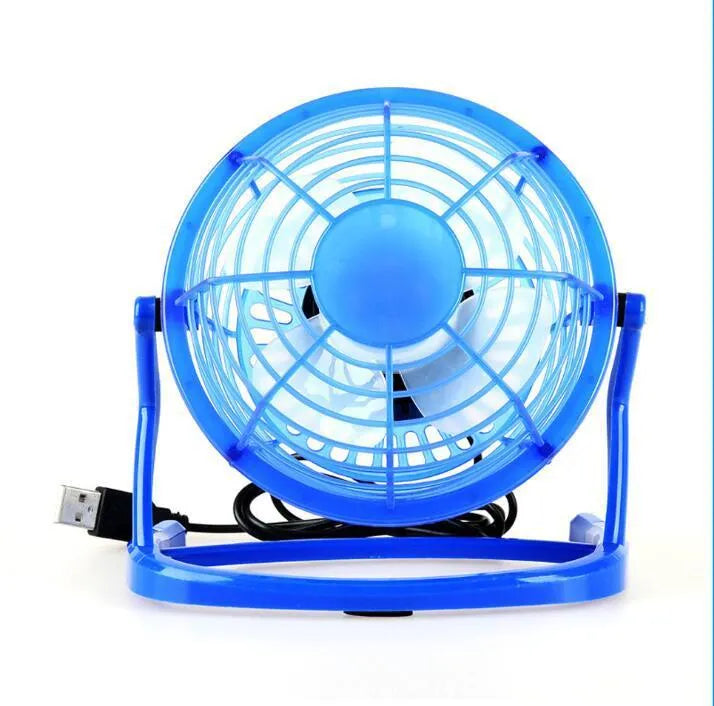 Compact black USB desk fan with adjustable tilt angle on a wooden desk next to a laptop