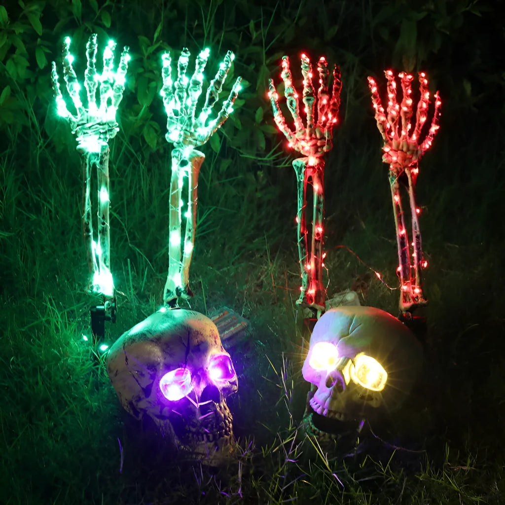 Purple plastic skeleton arm Halloween stake light illuminated in garden setting