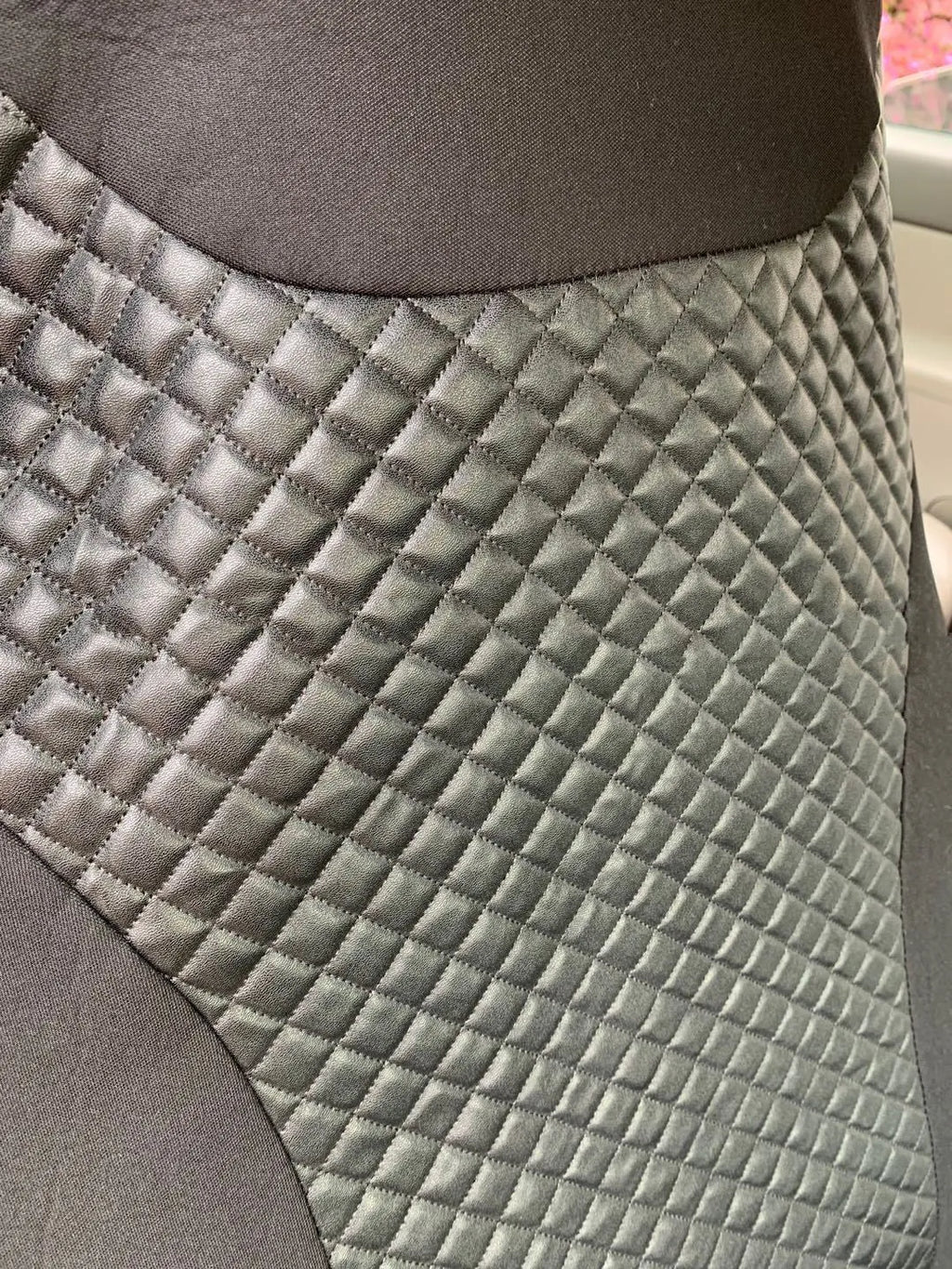 Black quilted automotive seat cover made from PU and polyester fabric on a car seat.
