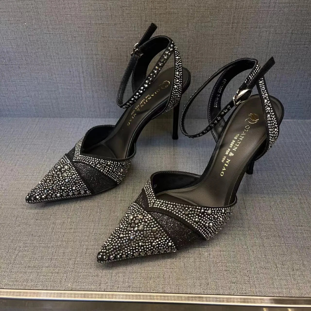 Black women's hollow high heels with pointed toe, stiletto heel, and red sole on a plain background.