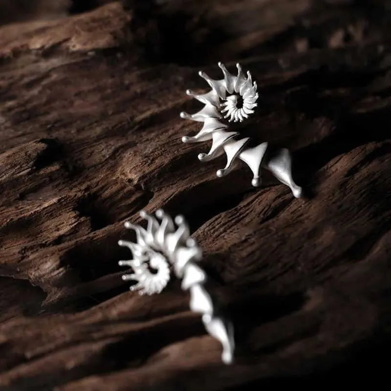 Matte finish three-dimensional conch-shaped alloy drop earrings on a plain background.