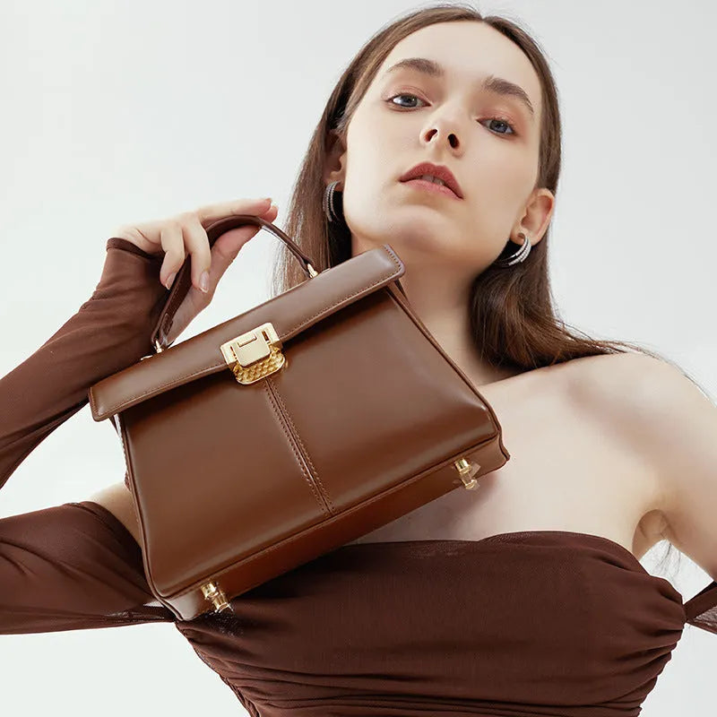 Black genuine leather women's shoulder bag with clasp closure showing square shape and adjustable strap