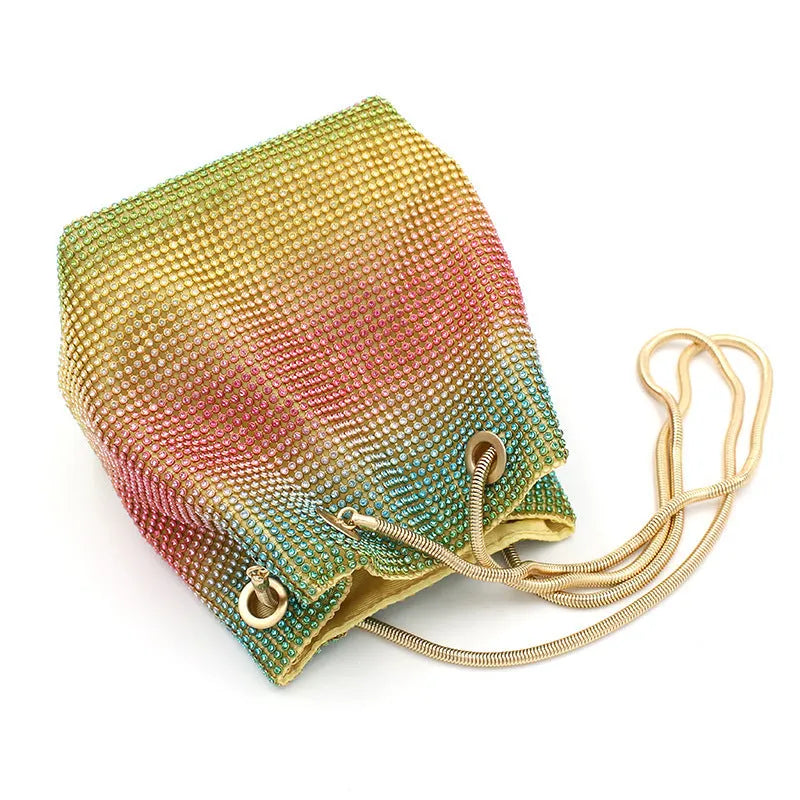 Rainbow coloured rhinestone bucket bag with a crossbody shoulder strap on a white background.