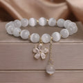 Women's white cat's eye stone bracelet with flower tassel detail and morganite safety buckle