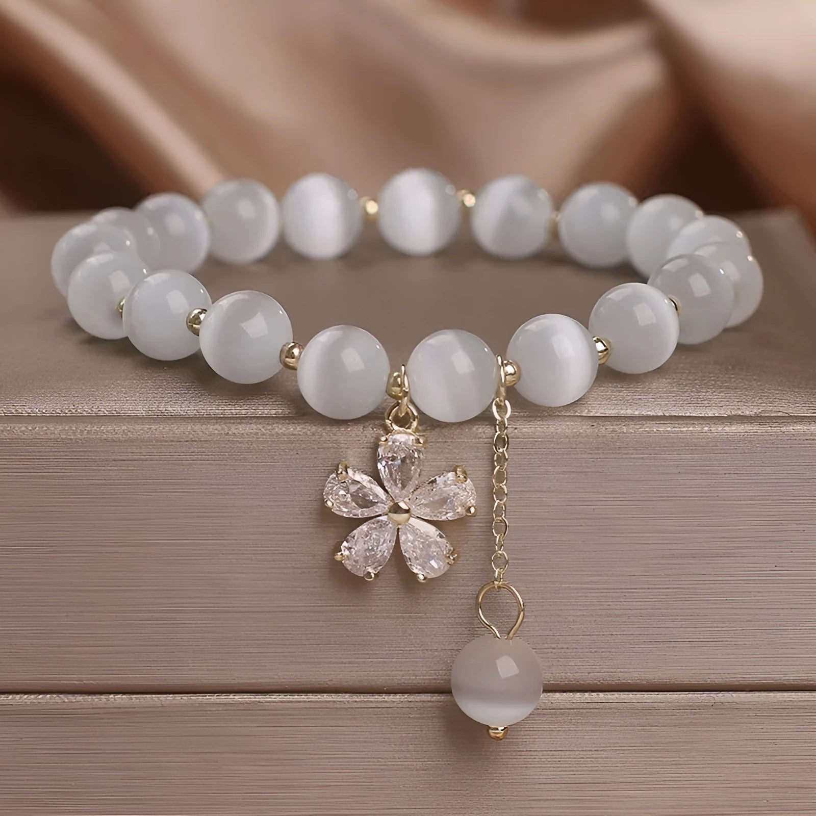 Women's white cat's eye stone bracelet with flower tassel detail and morganite safety buckle