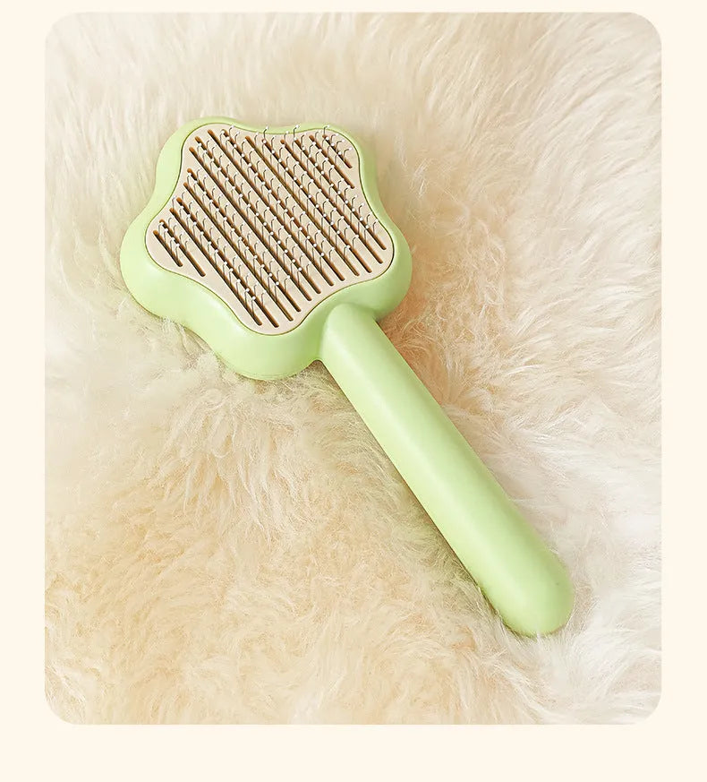 Green handle self-cleaning stainless steel needle comb for cats on a white background