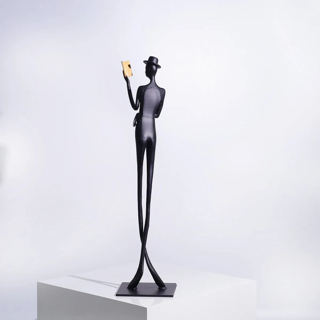 Black aluminium desktop sculpture of reading woman figure measuring 12x12x51cm