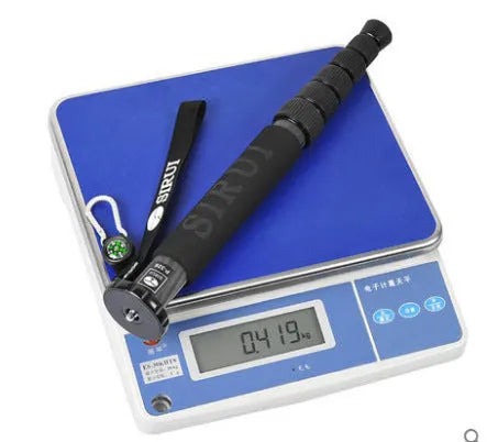 Black carbon fibre telescopic camera monopod fully extended next to a DSLR camera.