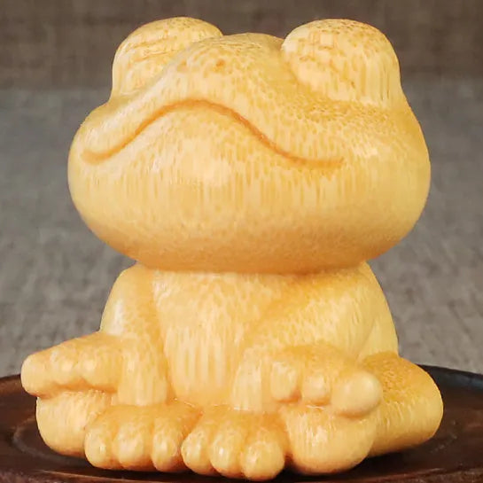 Solid bamboo carving ornament of a smiling cartoon frog, 5 cm tall.