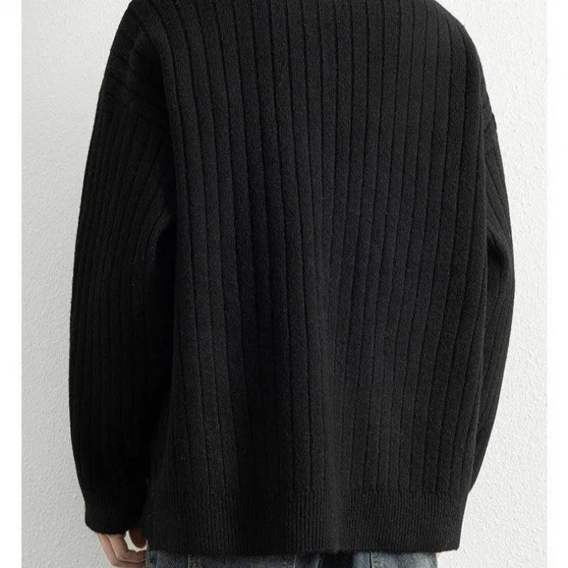 Man wearing a grey textured knit half zip sweater with a loose fit and long sleeves.