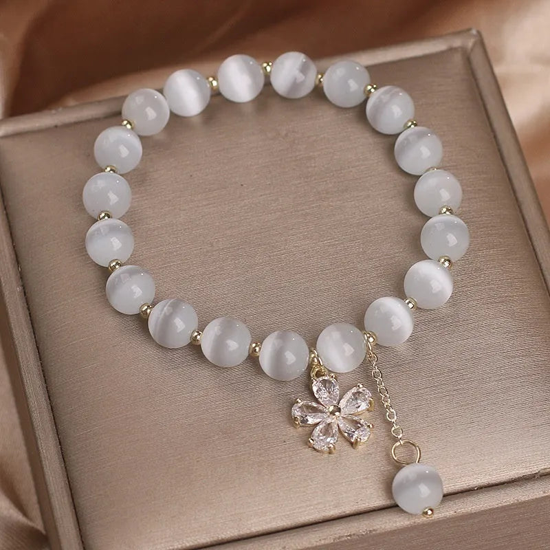 Women's white cat's eye stone bracelet with flower tassel detail and morganite safety buckle