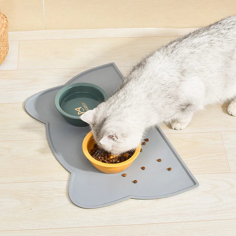 Blue silicone pet feeding mat with cat head design under food and water bowls