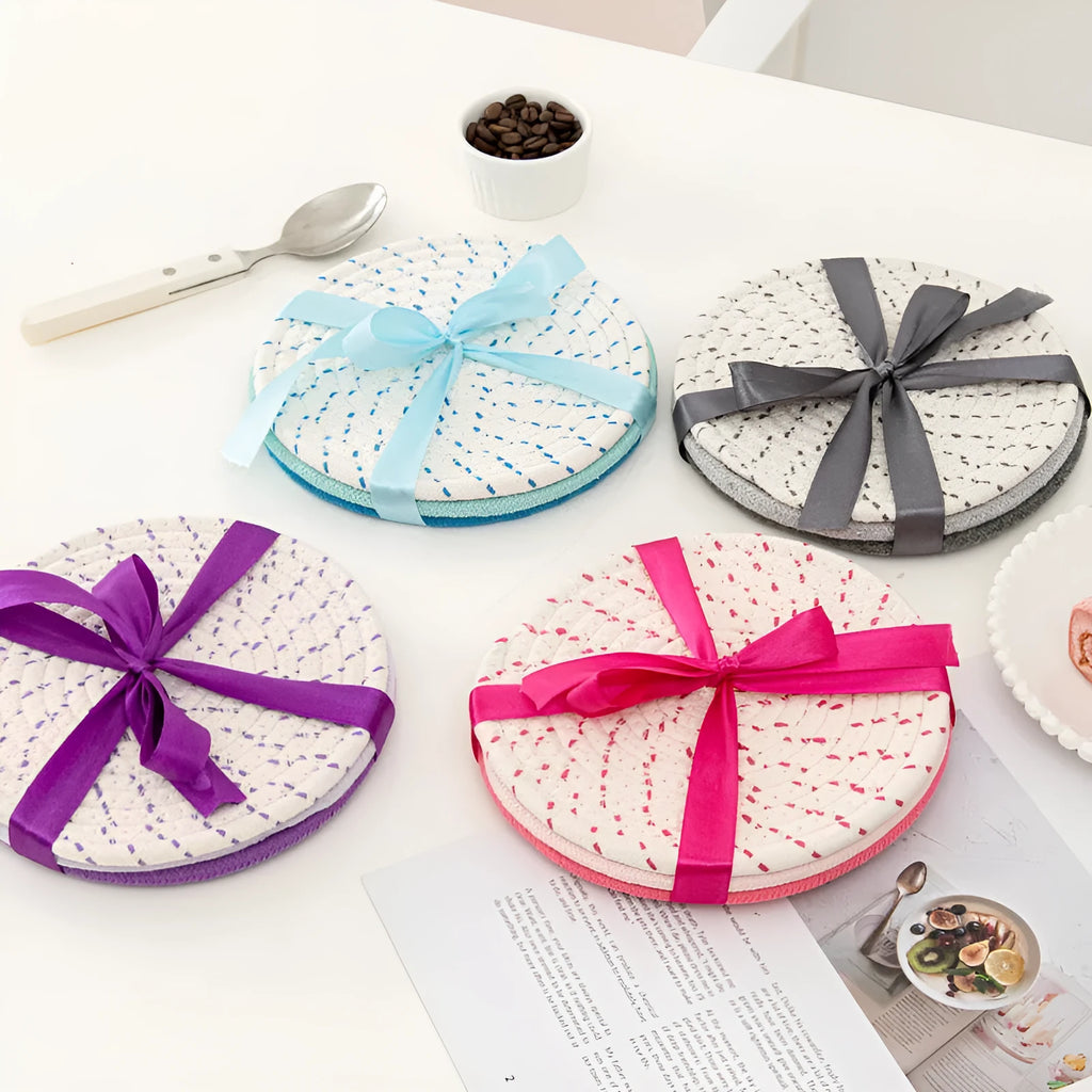 Set of three round grey cotton cord coasters on a wooden table