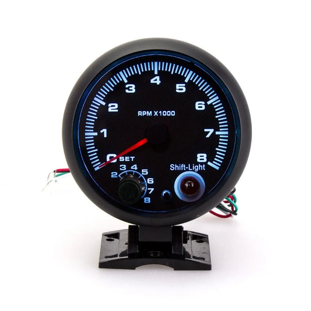 Black universal automotive tachometer with blue light pointer and scale showing rpm.