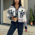 White women's zip-front cardigan sweater with contrast stripe pattern and lapel collar.
