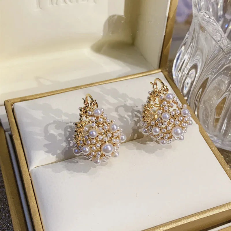 Women's gold flower basket earrings with small beads and pearl inlay detailing on copper
