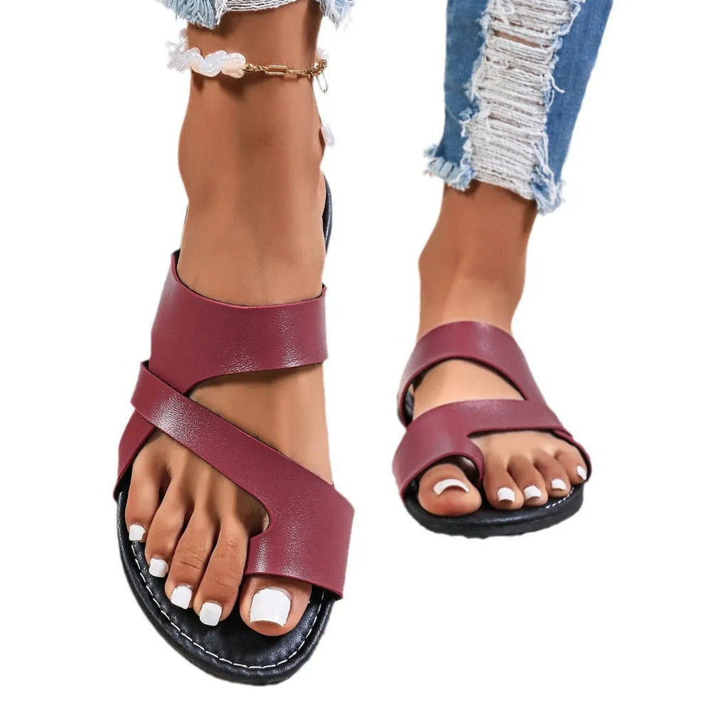 A pair of solid colour beach slippers with a round head, one-line design, and hollow-out details.