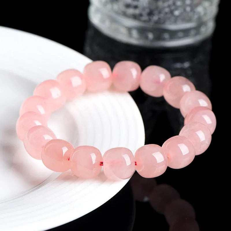 Pink natural crystal bracelet with barrel-shaped beads measuring 8 to 10 mm.