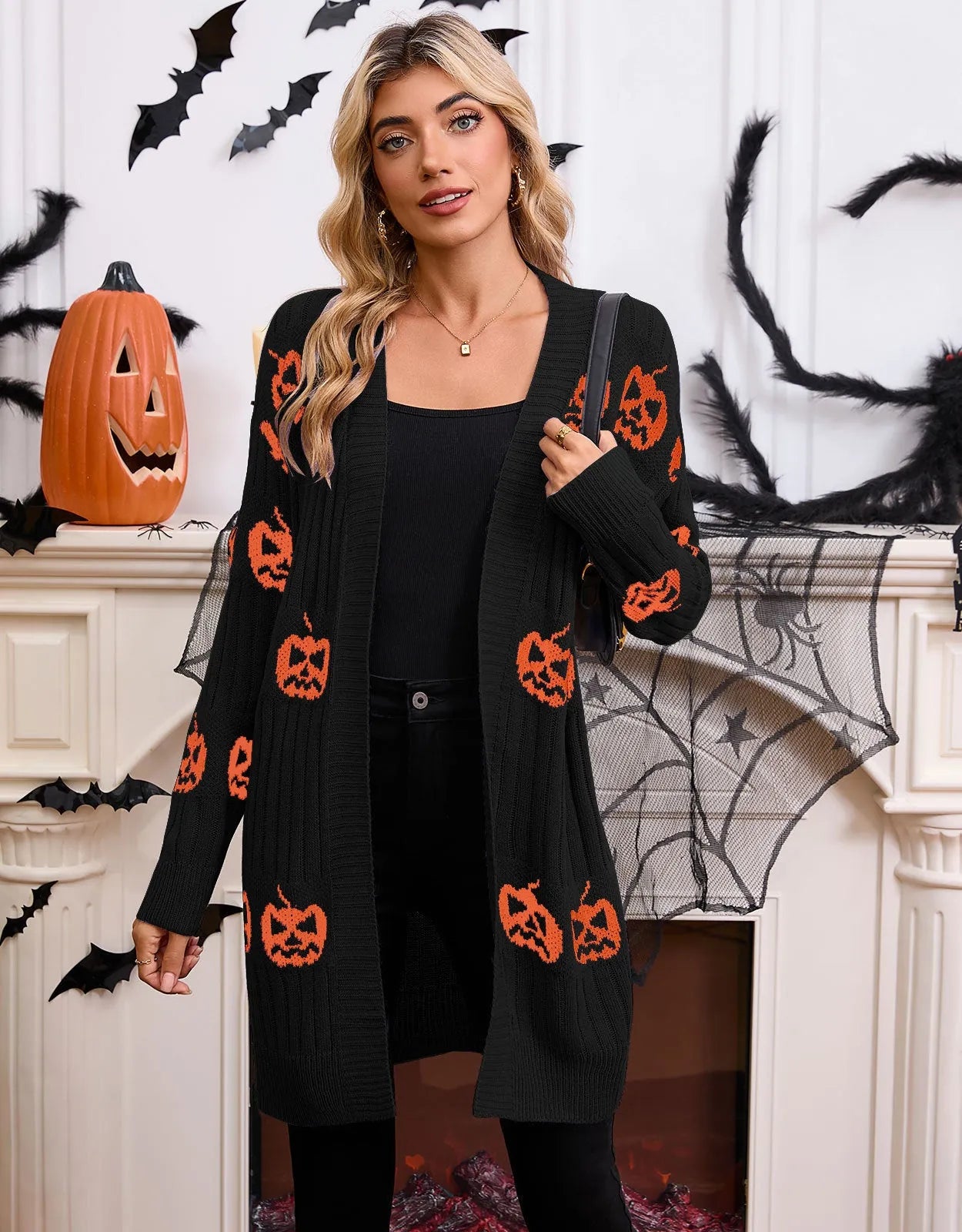 Women's black Halloween cardigan with orange pumpkin head jacquard pattern, shown as a straight-cut medium-length knit.