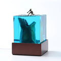 Epoxy resin shark surf scene night light ornament in 5cm and 8cm sizes on a table.
