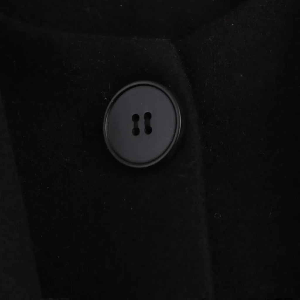Women's long black polyester overcoat with a gray artificial fur collar, showing street fashion style and front pockets.