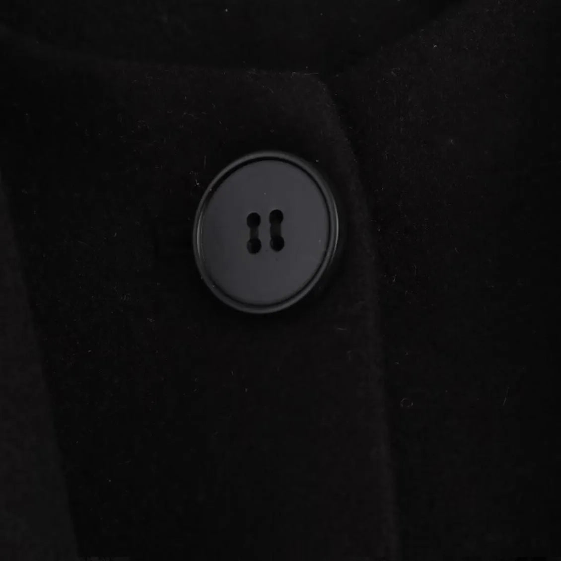 Women's long black polyester overcoat with a gray artificial fur collar, showing street fashion style and front pockets.