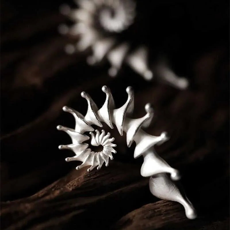 Matte finish three-dimensional conch-shaped alloy drop earrings on a plain background.