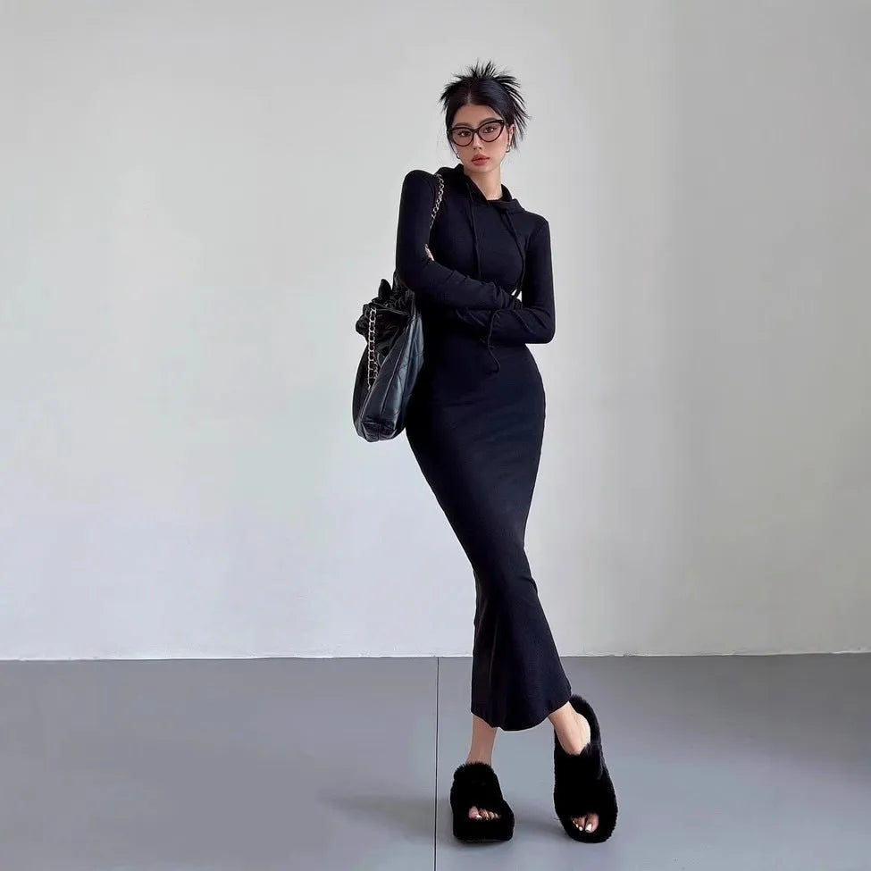 A woman wearing a light grey hooded long sleeve sheath dress with a high waist.
