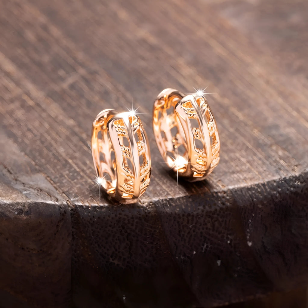 Rose gold coloured copper earrings with a hollowed leaf design and small heart detail.