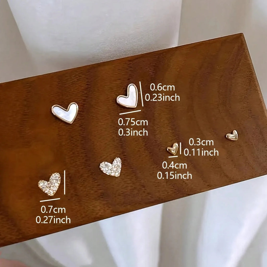 Three pairs of heart-shaped girly earrings in gold, black, black and white, and pink colours
