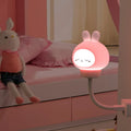 White cartoon bear-shaped USB night light with remote control on a wooden table.