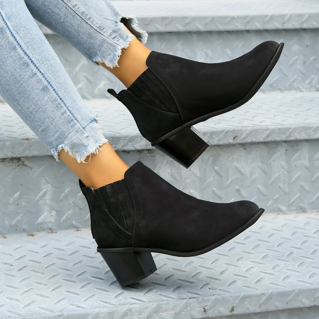 Women's black pointed toe ankle boots with a thick square low heel and slip-on design.