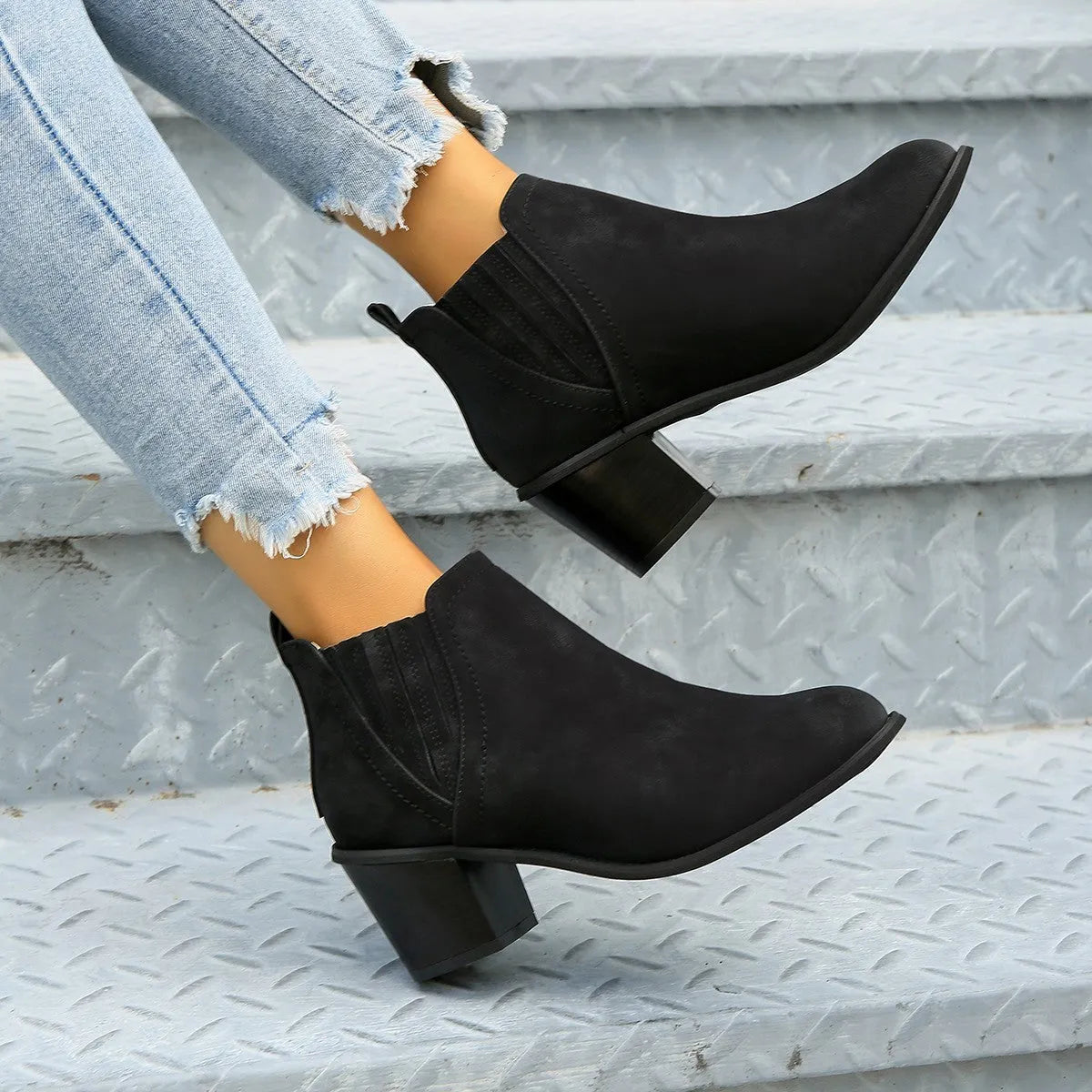 Women's black pointed toe ankle boots with a thick square low heel and slip-on design.