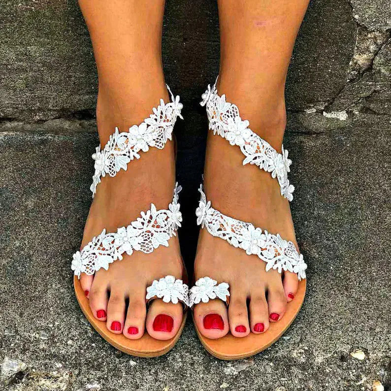 White women's flat sandals with rhinestone and floral decoration on the strap.
