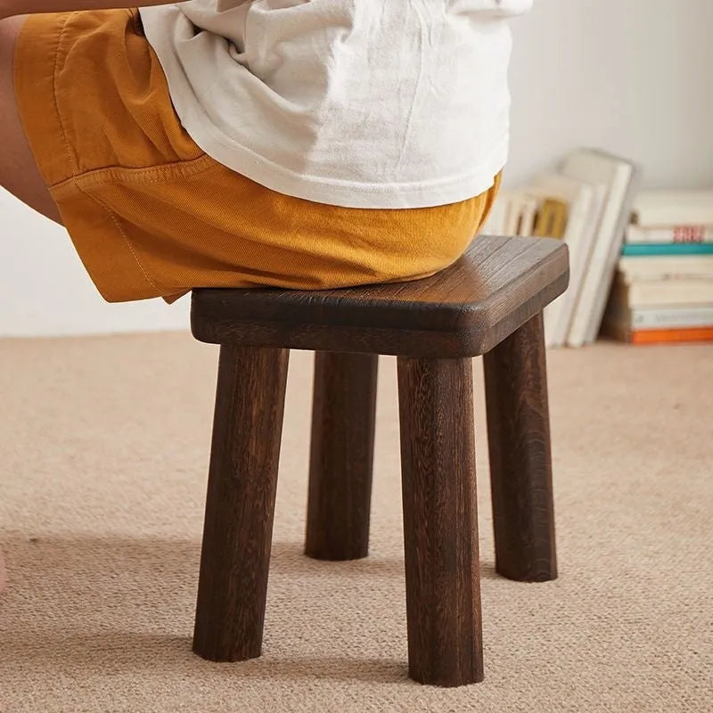 Solid wood shoe changing stool with distressed finish and bracket structure in a living room setting