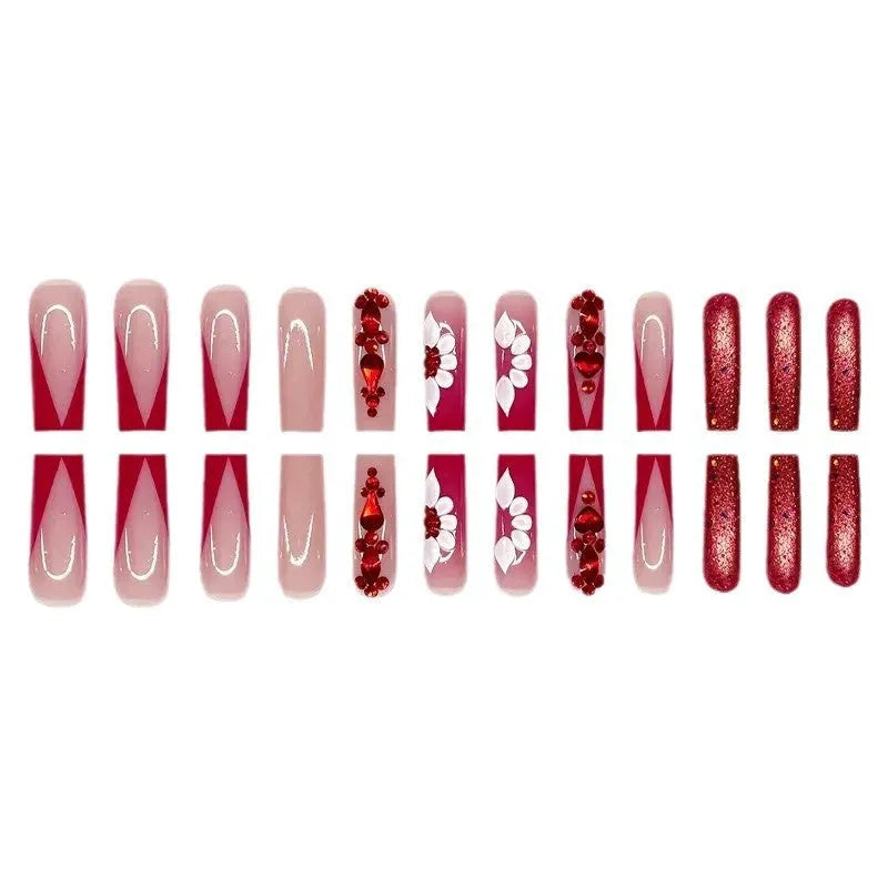 Long coffin shaped press-on false nails with red diamond gemstone and sweet flower pattern decoration.