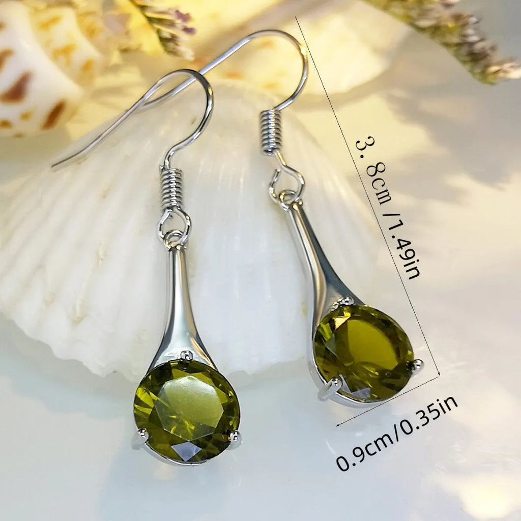 Olive green topaz coloured drop-shaped retro earrings for women on a plain background.
