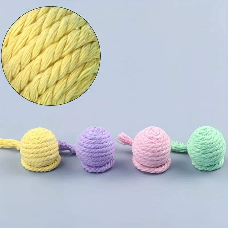 Colourful cat toy ball with an attached rope and an internal bell, shown in green, pink, purple and yellow.