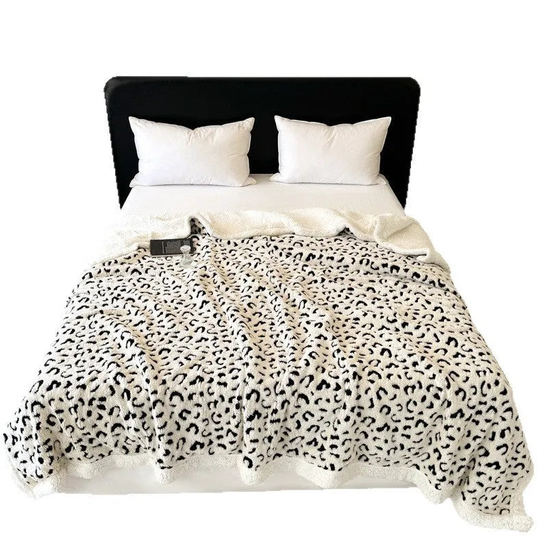 Double-layer jacquard taffeta blanket with leopard print pattern in camel colour on a bed.