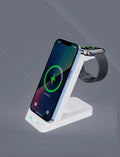 Black three-in-one wireless charging station dock for phone, smartwatch, and earbuds on a desk.