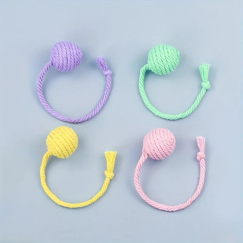 Colourful cat toy ball with an attached rope and an internal bell, shown in green, pink, purple and yellow.