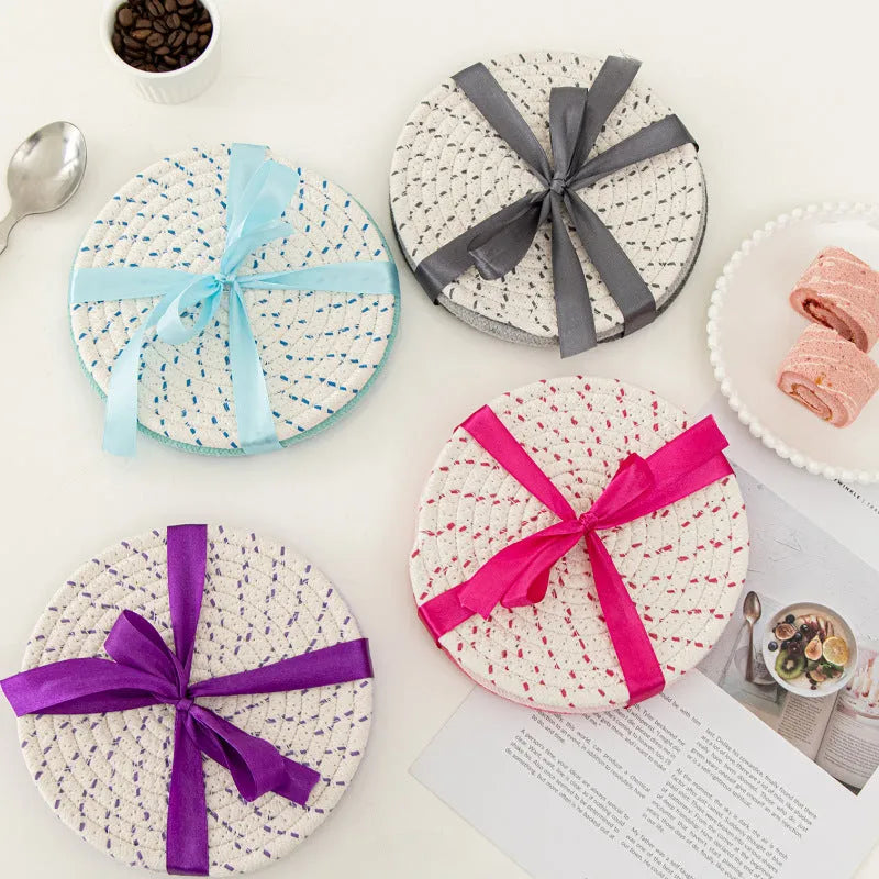 Set of three round grey cotton cord coasters on a wooden table