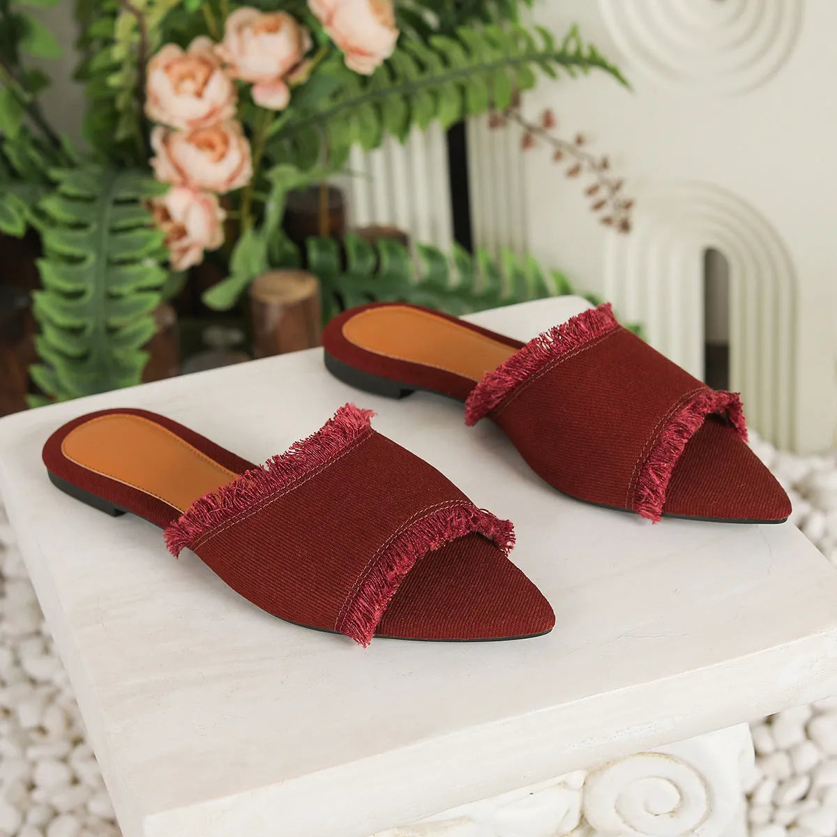 Women's denim flat slippers with tassel detail in apricot colour on a white background.