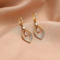 A pair of women's zircon teardrop tassel earrings with gold metal buckles on a white background.