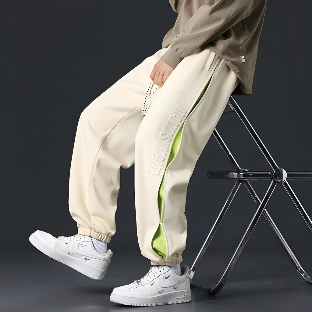 Men's grey green cotton casual trousers with white collage stitching detail and an elasticated ankle band.
